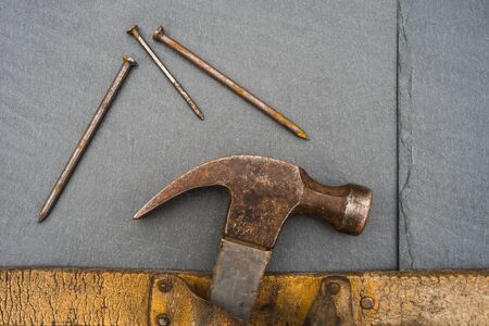 Roofers hammer and nails in detail on natural slate with copy space
