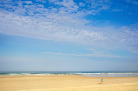 Landscape running jogger on wide sandy beach in summer