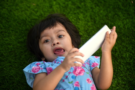 Cute Little girl playing with mobile phone at Parkの写真素材