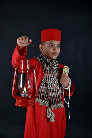 Muslim boy holding The Holy Koran and lantern