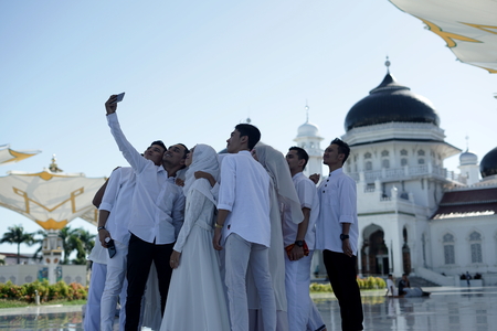 Banda Aceh, Aceh Province / Indonesia - June 3 2018 :Tourists are taking pictures/selfie in front of Baiturrahman grand mosque in Banda Aceh, Indonesia.のeditorial素材