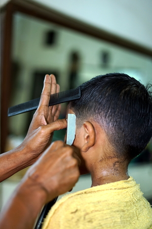 Little Boy Getting Haircut By Barber While Sitting In Chair At Barbershopの写真素材