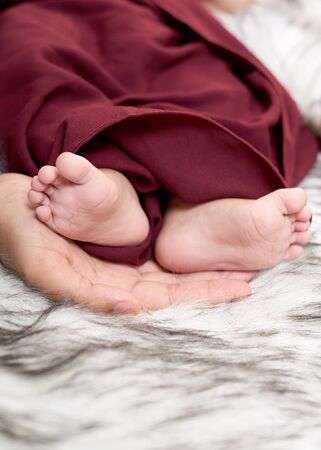 Baby feet in mother hands. Tiny Newborn Baby's feet on female Shaped hands closeup. Beautiful conceptual image of Maternityの写真素材