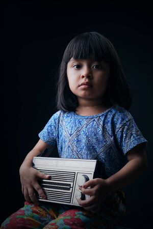 Cute little girl listening to the old radioの写真素材