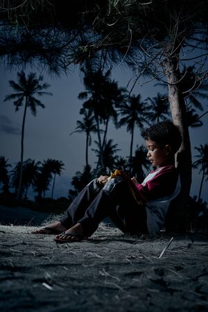 Schoolboy doing homework outdoor under the sky at night
