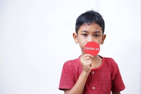 Asian boy holding Covid-19 sticker. Conceptual image for Stop the coronavirus spreading
