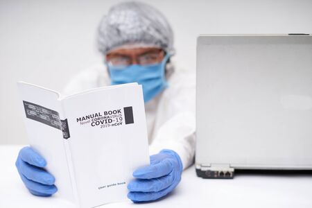 Doctor reading a Medical Book of novel coronavirus in office desk. Coronavirus Research concept
