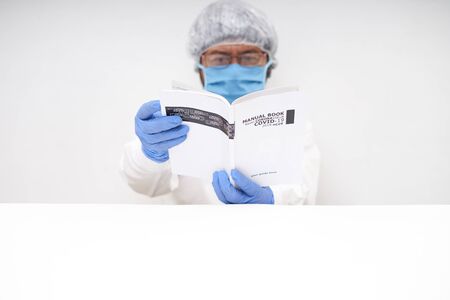 Doctor reading a Medical Book of novel coronavirus in office desk. Coronavirus Research conceptの写真素材