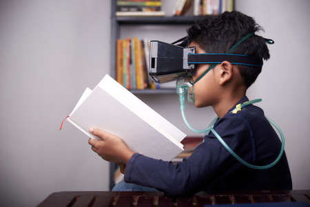 little Boy wearing VR headset and nebulizer mask studying at home quarantineの写真素材