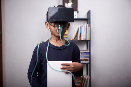 little Boy wearing VR headset and nebulizer mask studying at home quarantineの写真素材