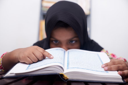 Little girl praying and reading Koran at homeの写真素材