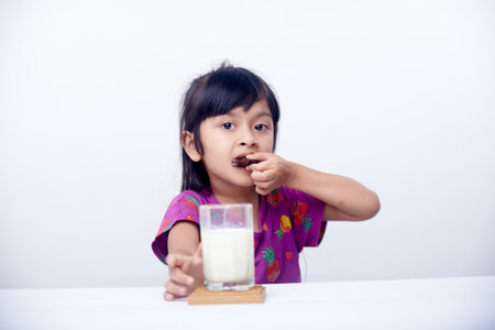 Happy little girl eating biscuits with milk fresh milk for breakfastの写真素材