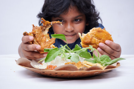 Asian little Girl Holding Fried Chicken with vegetable in white backgroundの写真素材