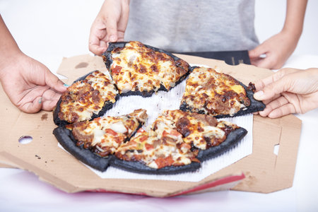 Pizza in a box with the hands of a man and a womanの写真素材