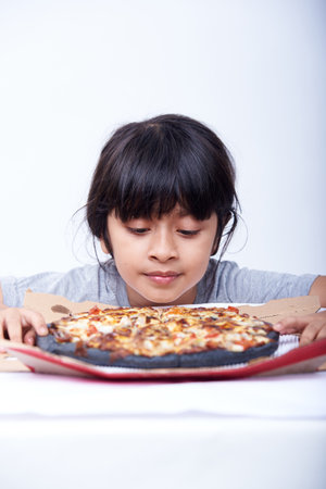 Young Asian girl eating pizza on white background, closeup shot.の写真素材