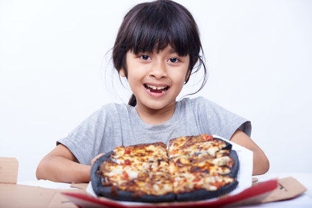 Little asian girl eating pizza on white background. Isolated.の写真素材