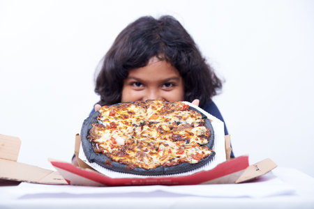 Little girl eating pizza. Isolated on a white background.の写真素材