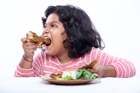 Hungry little girl eating Delicious Fried Fish with rice and vegetableの写真素材