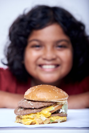 A little girl with an appetizing burger, Close-up focus on Burgerの写真素材