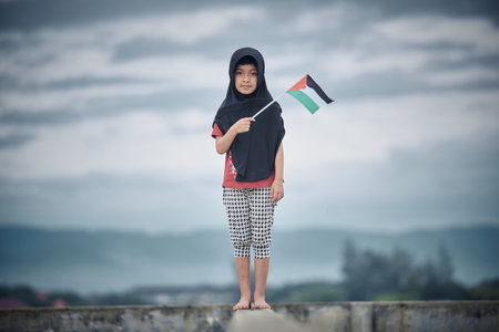 Cute Little girl waving Palestine Flag sends a powerful message of support and empathy to the worldの写真素材