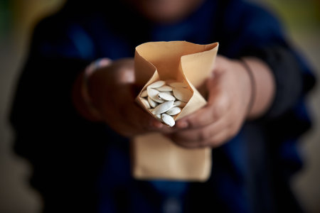 pumpkin seeds in a paper bag in the hands of a child.の写真素材