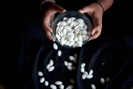 Pumpkin seeds in a glass bowl on a black background.の写真素材