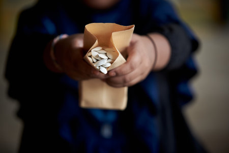 pumpkin seeds in a paper bag in the hands of a child.の写真素材