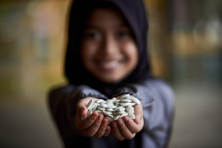 Little girl holding a pile of healthy pumpkin seedsの写真素材