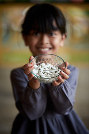 Close-up of a little girl holding a bowl of pumpkin seedsの写真素材