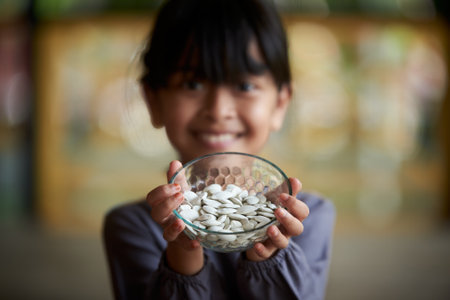 Little girl holding a pile of healthy pumpkin seedsの写真素材