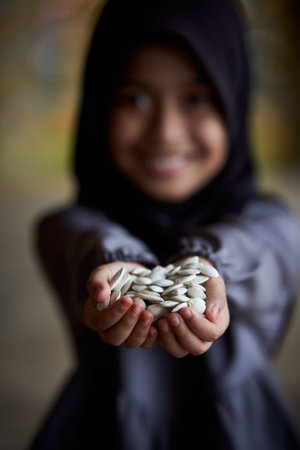 Little girl holding a pile of healthy pumpkin seedsの写真素材