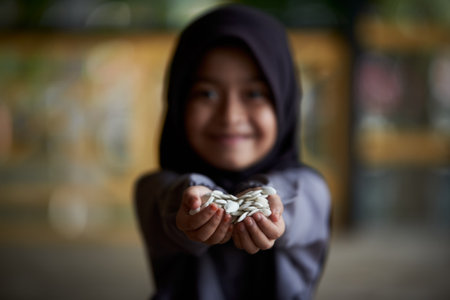 Little girl holding a pile of healthy pumpkin seedsの写真素材