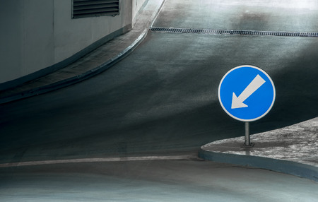 Underground parking level with direction to the left on blue sign with white arrowの写真素材