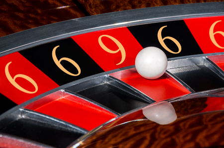 Concept of classic casino code 6-6-9-6-6 lucky numbers roulette wheel with black and red sectors and white ballの写真素材