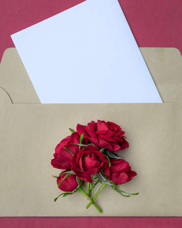 Envelope with a bouquet of red tea roses with space for design. Postcard.