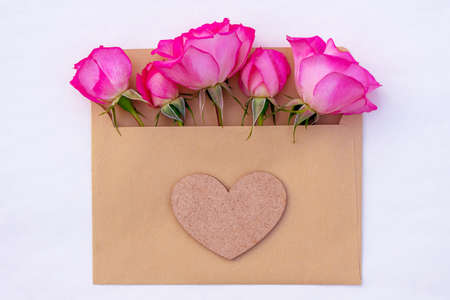 Pink roses in an envelope with a heart isolated on white background