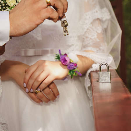 romantic photo of bride and groom close-up hands and lock with keysの写真素材