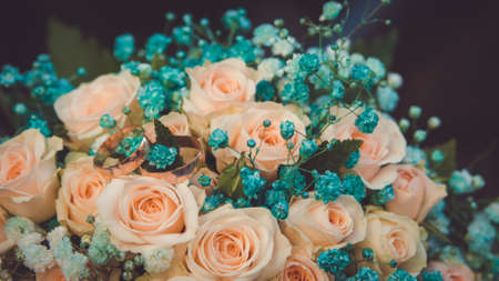 Delicate romantic bridal bouquet of peach roses with wedding ringsの写真素材
