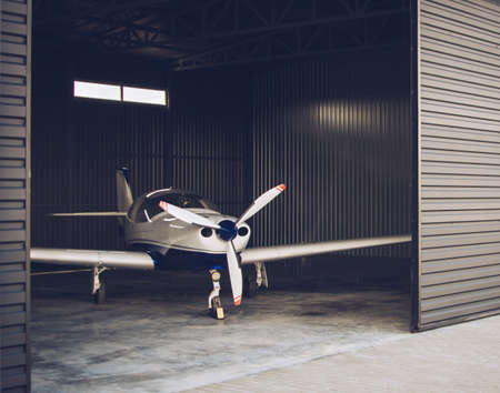 Small white private jet parked in the hangar