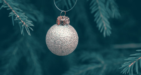 Background of green twigs of a Christmas tree with shiny colorful ball.の写真素材