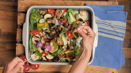 Kitchen flat lay: hands holding vegetable skewer over cut vegetable cubes for barbequeの写真素材