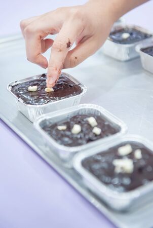 Hand of woman making decorate marshmallow on chocolate brownie is in the kitchenの写真素材