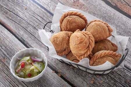 Traditional curry puffs stuffed chicken on wooden table as background.の写真素材