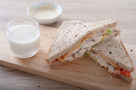 Sandwiches with tomato, chicken, ham, cheese and mayonnaise on wooden board as backgroundの写真素材