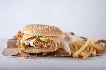 Crispy chicken burger with cheese and mayonnaise sauce on wooden table backgroundの写真素材
