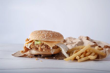 Crispy chicken burger with cheese and mayonnaise sauce on wooden table backgroundの写真素材
