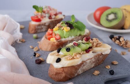 Sandwiches with banana, kiwi, grains and mayonnaise on gray board as backgroundの写真素材