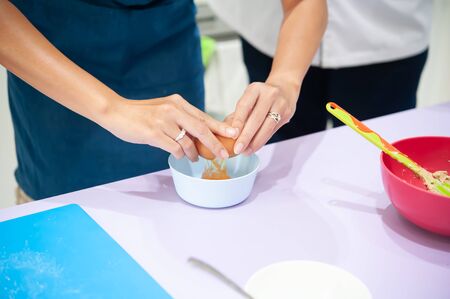 Broken an egg yolk in the hands female for made bakery ingredient and cookingの写真素材