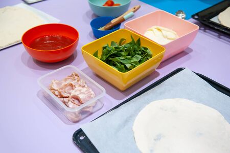Homemade raw pizza dough with ingredients tomato sauce, cheese, basil, bacon and fresh tomatoの写真素材
