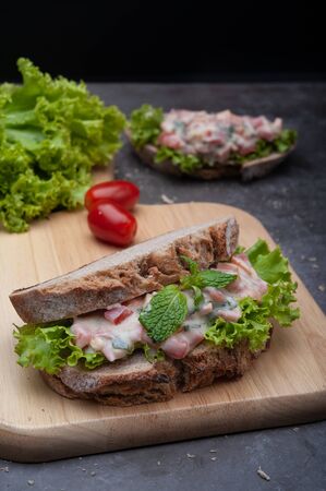 Healthy breakfast sandwiches with tomato, lettuce on gray board as backgroundの写真素材